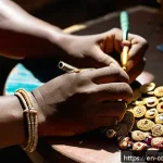 Home 19 코모로 기념품 쇼핑 가이드 - A close-up shot of a skilled artisan’s hands crafting traditional Comorian jewelry in a sunlit works...